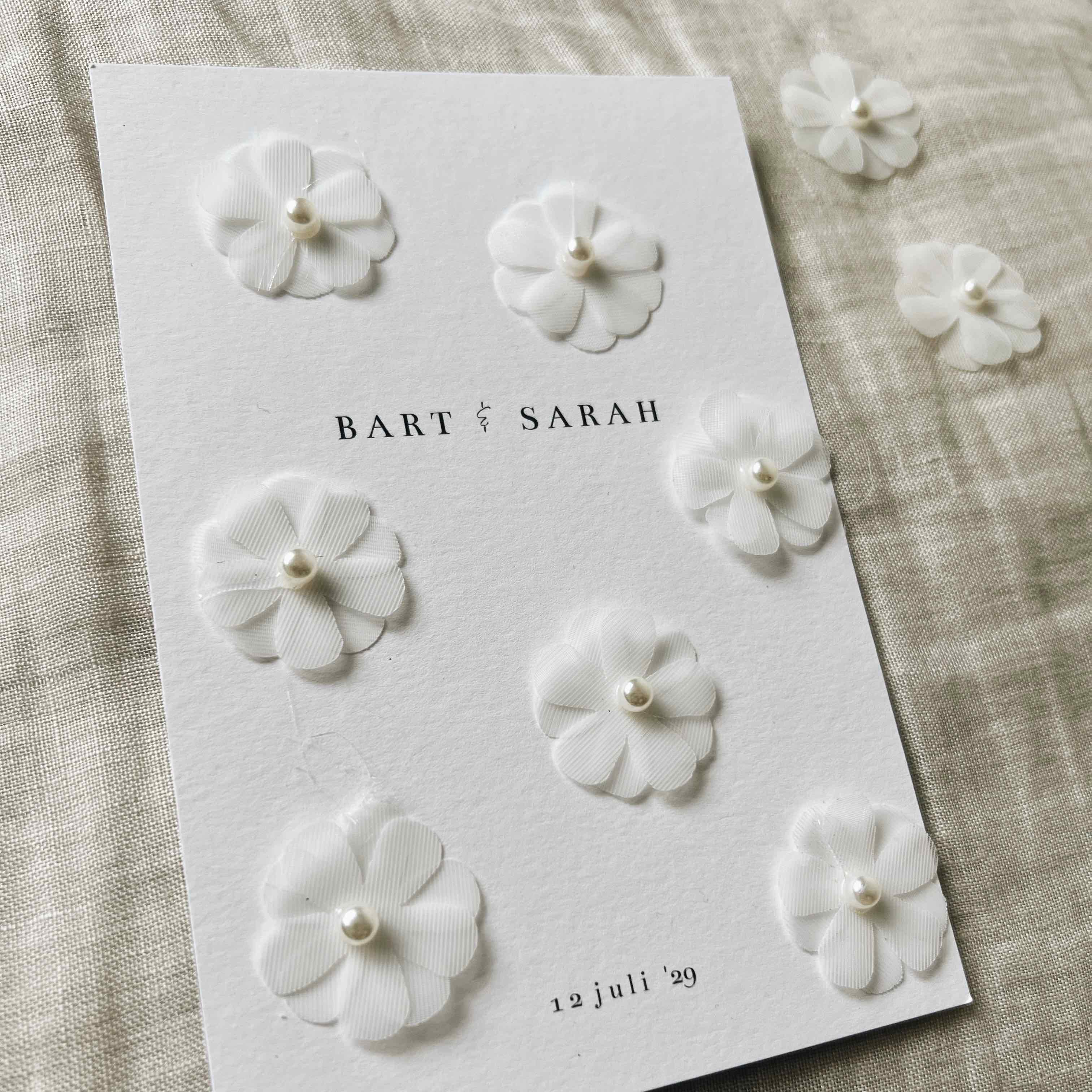 Klassieke trouwkaart met witte bloemetjes en parels erop geplakt
