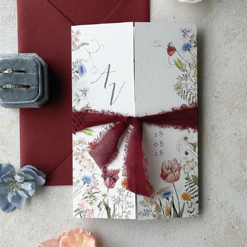 Luikvouw trouwkaart met wilde bloemen en illustratie van trouwlocatie