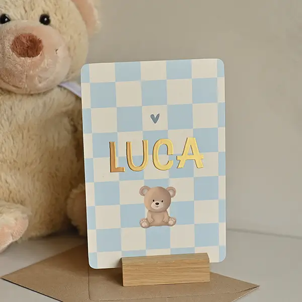 Stoer geboortekaartje met koel blauwe ruitjes, folie en teddy beertje