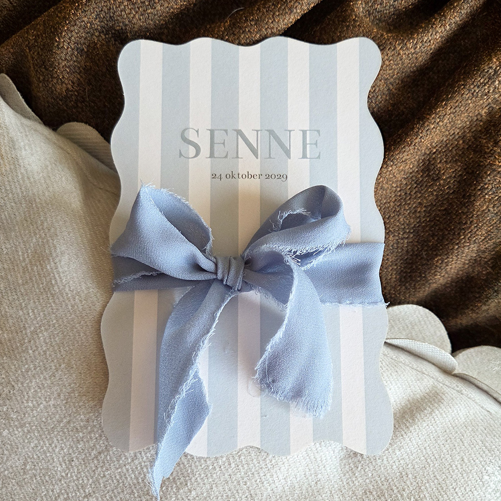 Golvend geboortekaartje voor een jongen met strik en zachte kleuren