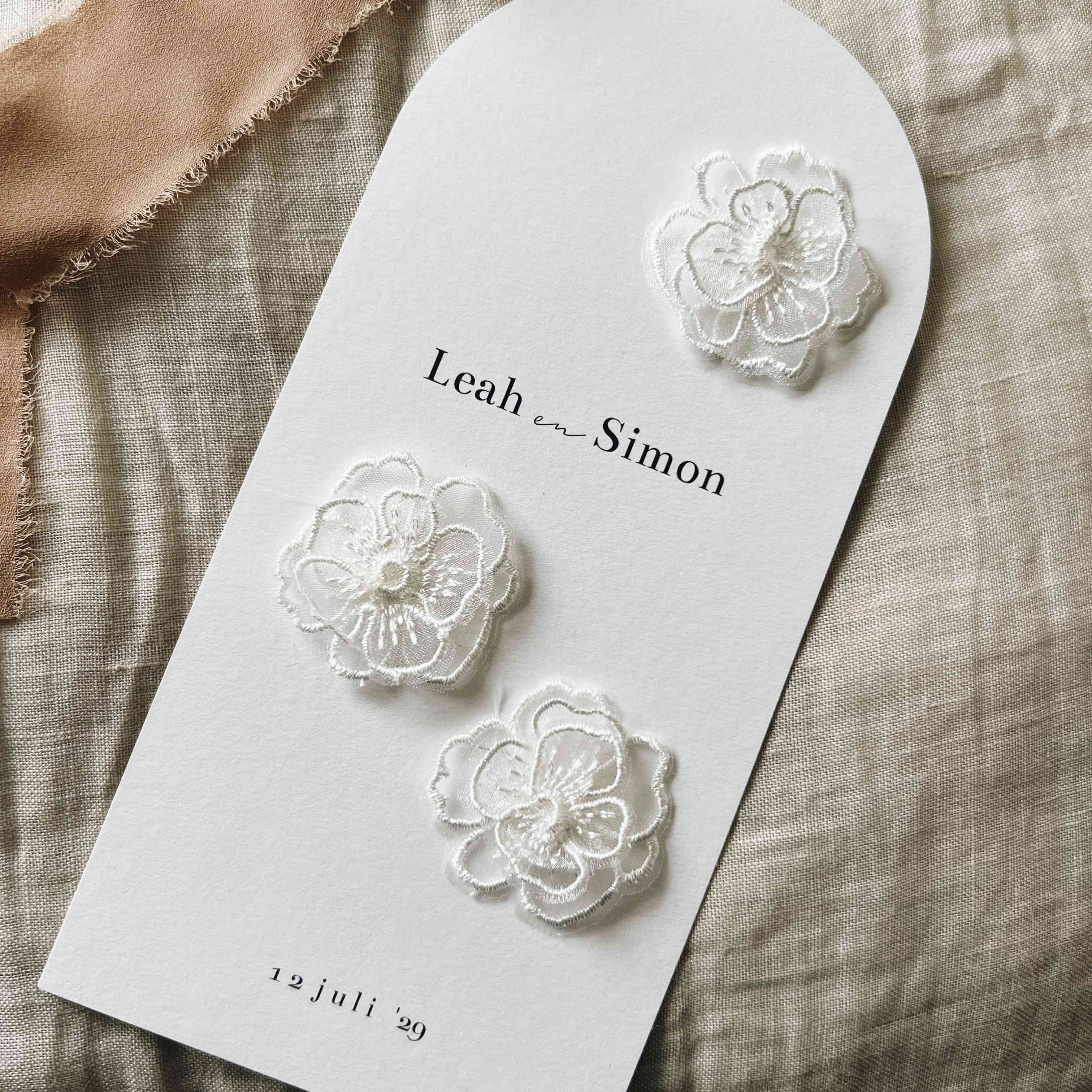 Klassieke trouwkaart met kanten witte bloemen erop geplakt