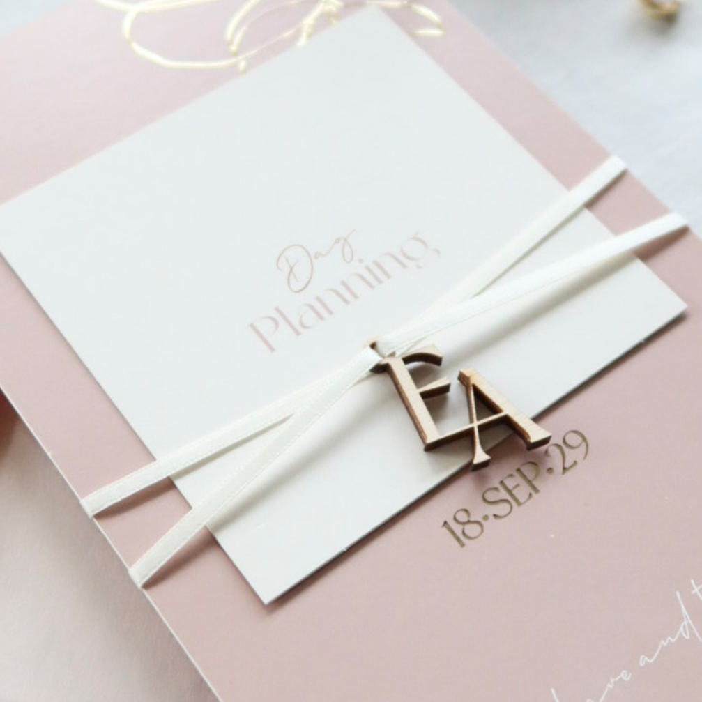 Moderne trouwkaart in roze en roestbruin met labels en initialen