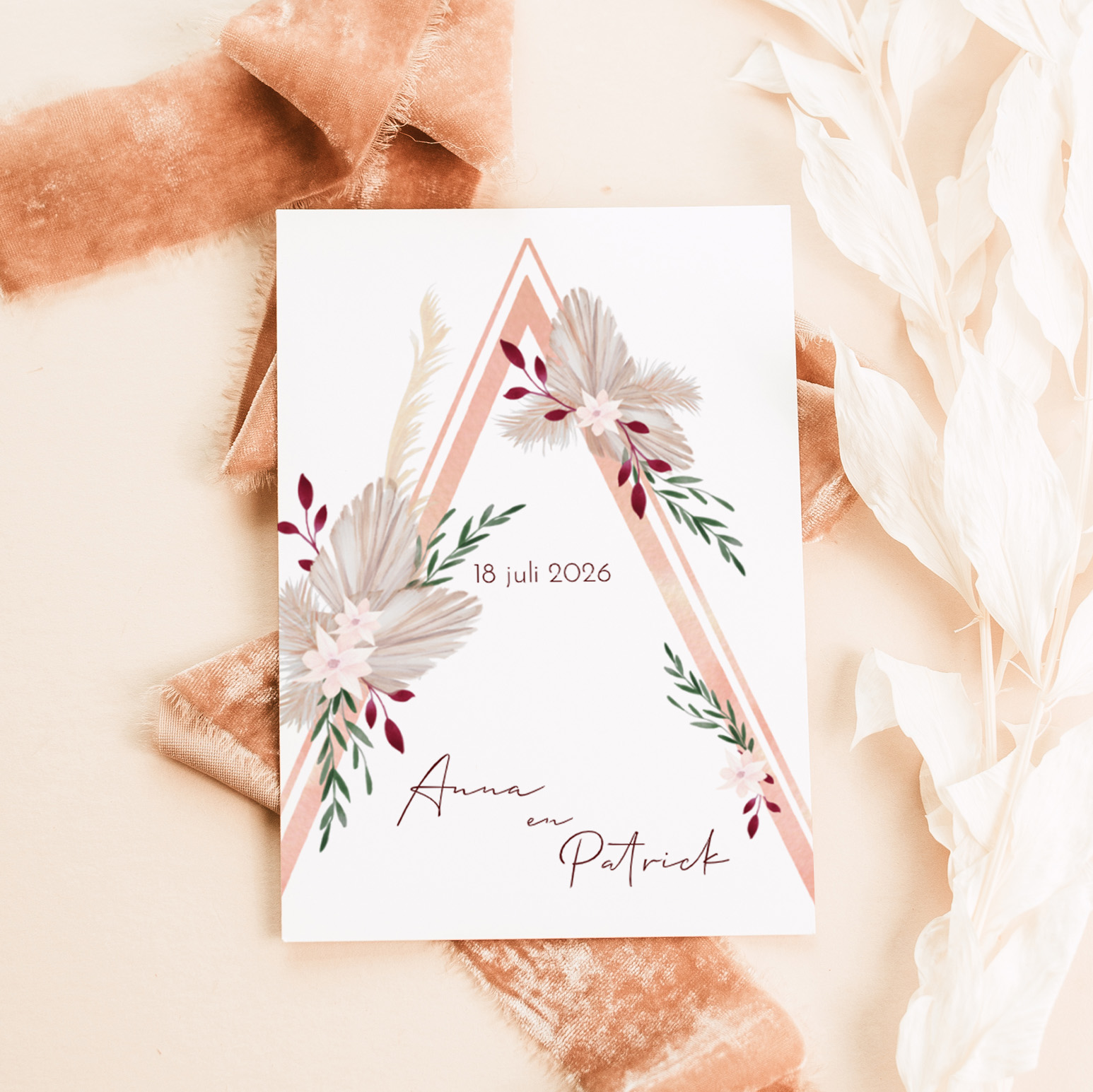 Boho trouwkaart met droogbloemen en driehoekvorm.