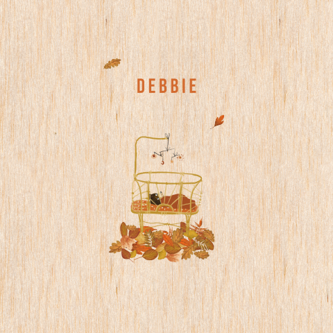 Geboortekaartje van hout met beertje in een wieg en herfstbladeren