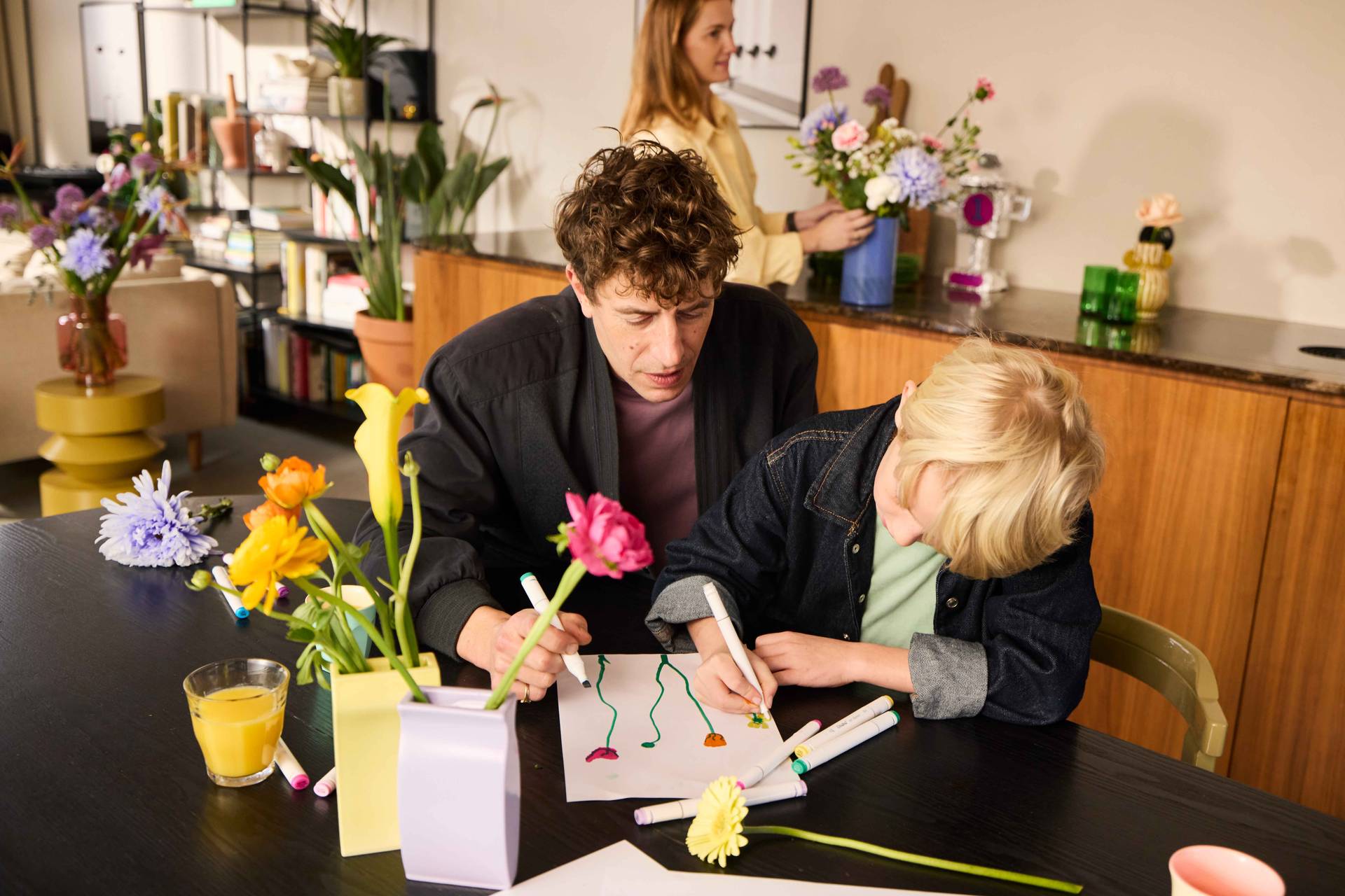 Vader met kinderen in de keuken waar bloemen staan