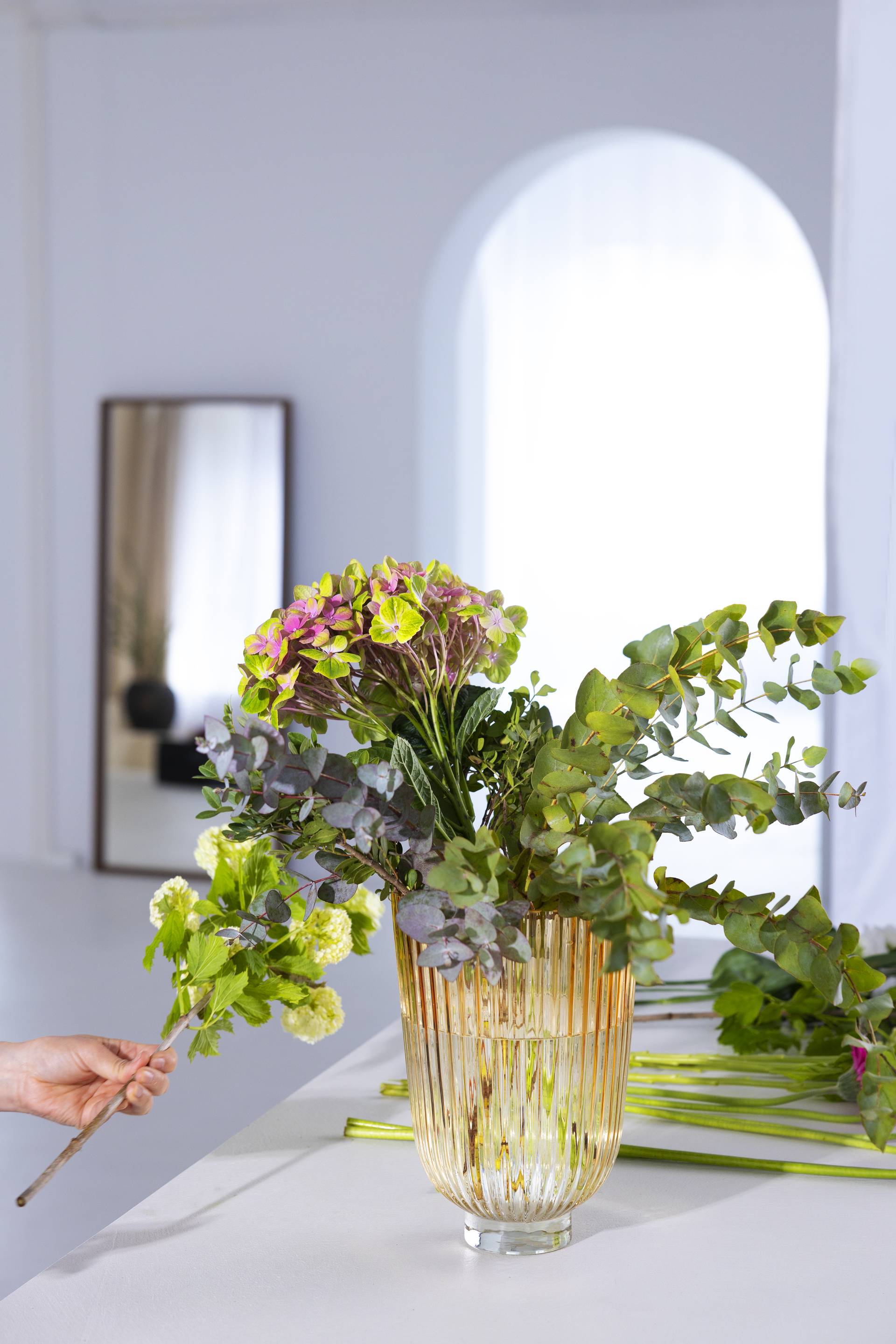 Glazen vaas met groot boeket met paars, roze en groene bloemen