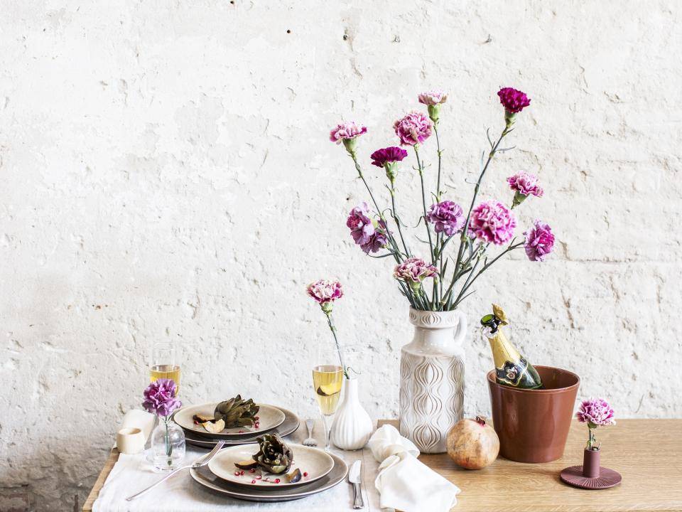 Rustieke tafelsetting met bloemen, glazen, borden en een ijsbucket.