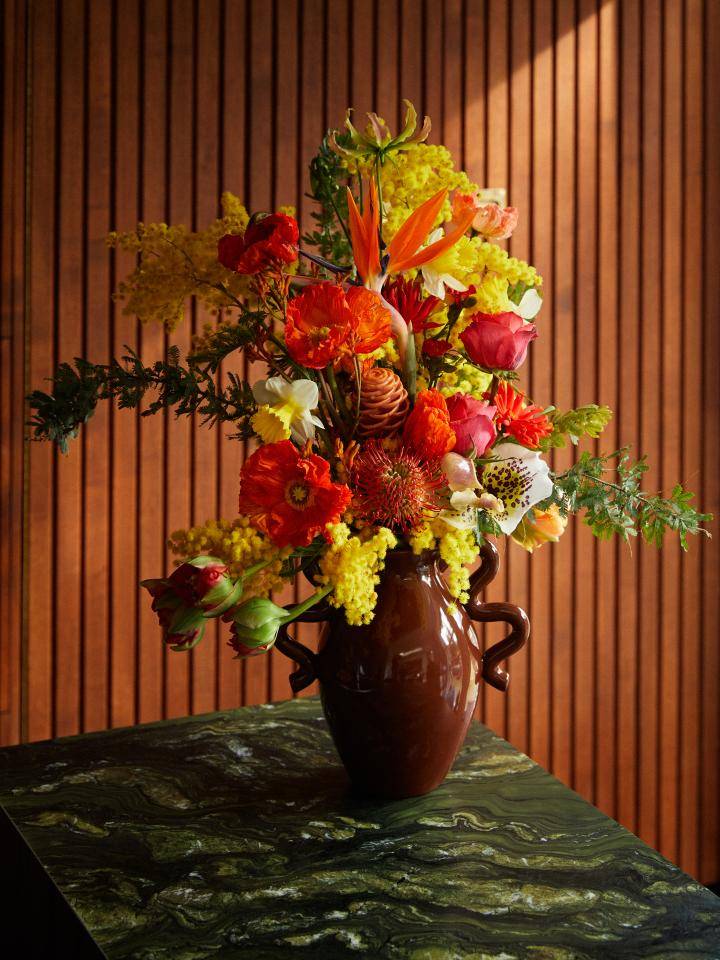 Twee boeketten met typische winterbloemen, waaronder amaryllis en helleborus, op een houten tafel.