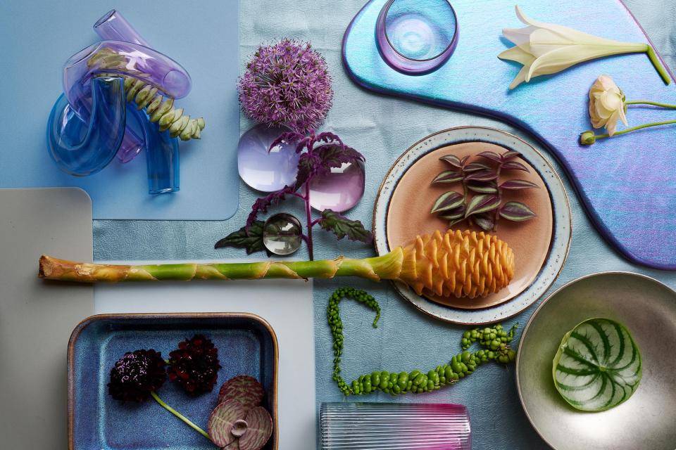 Verschiedene Blumen und Pflanzen auf einer bunten Hintergrund mit Glasobjekten und Keramikschalen.
