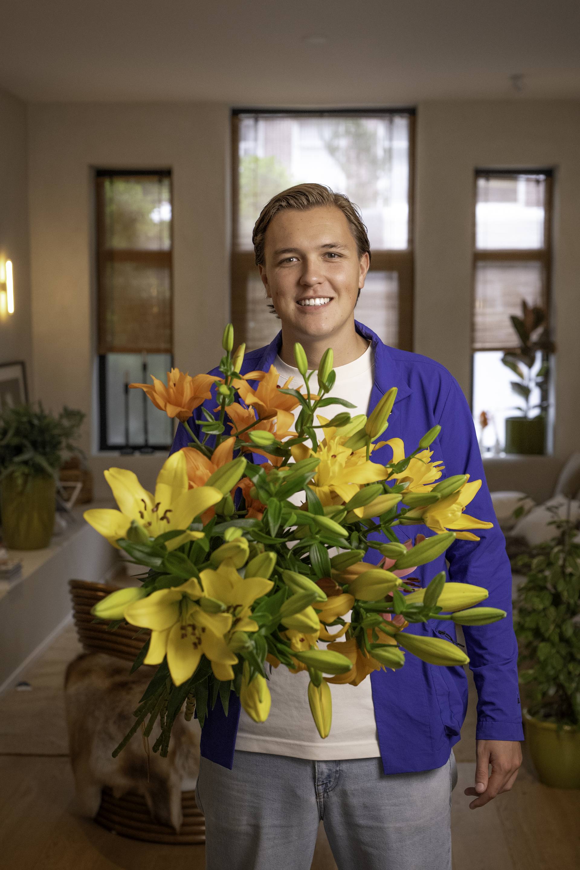 jong volwassene met boeket gele en oranje lelies in de hand in huiskamer