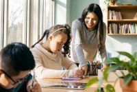 Meisje met een beperking krijgt hulp van een vrouw tijdens het schrijven.