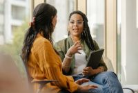 Hulpverlener in gesprek met cliënt tijdens een persoonlijk gesprek in een rustige ruimte.