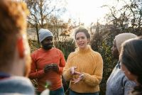 Sociaal werker voert een groepsgesprek met volwassenen in een buitenomgeving.
